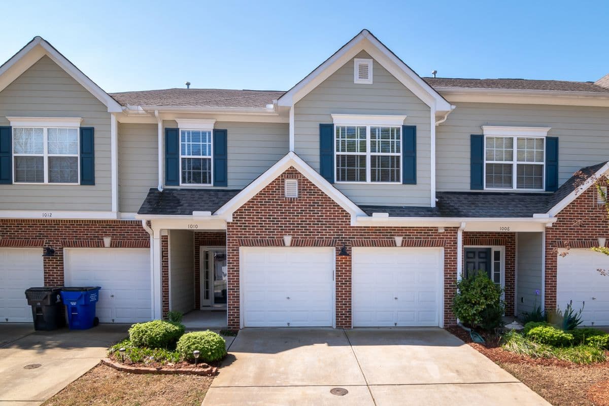 A row of newly built, attainable townhomes with tidy landscaping on a quiet street.