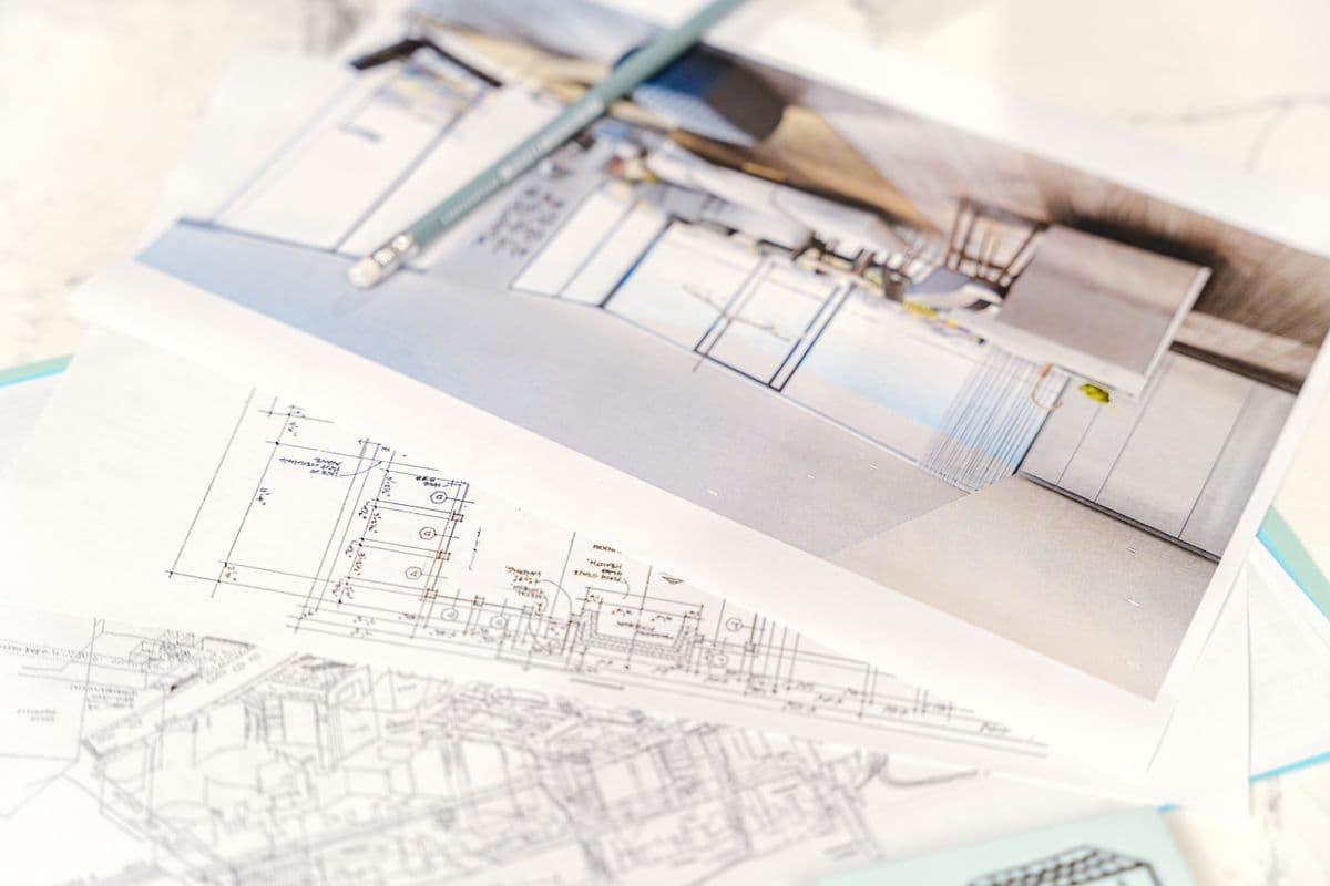 Architectural floor plans and a design rendering laid out on a desk during project planning.
