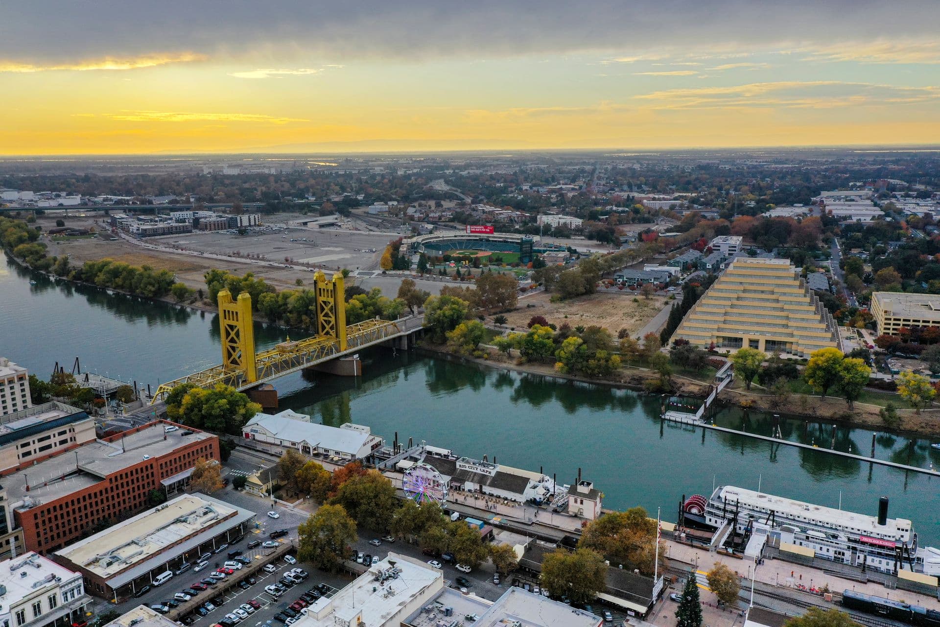 The Tower Bridge over the Sacramento River at sunset, with the downtown Sacramento skyline beyond.